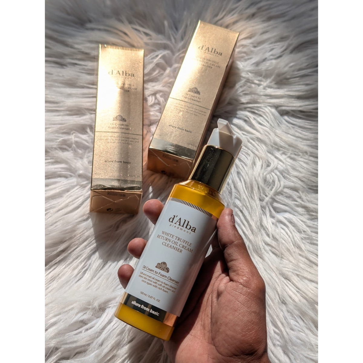 d'Alba White Truffle Return Oil Cream Cleanser 150ml bottle held in hand with two gold boxes