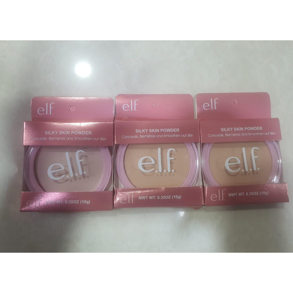 Three e.l.f. Silky Skin Powder compacts in pink packaging in three tones