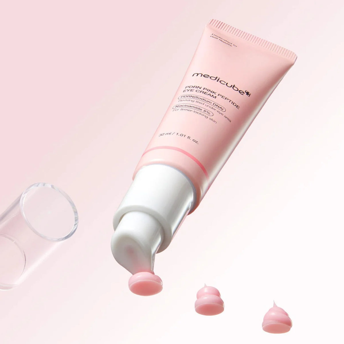 Medicube PDRN Pink Peptide Eye Cream — pink eye cream tube with cream drops studio shot